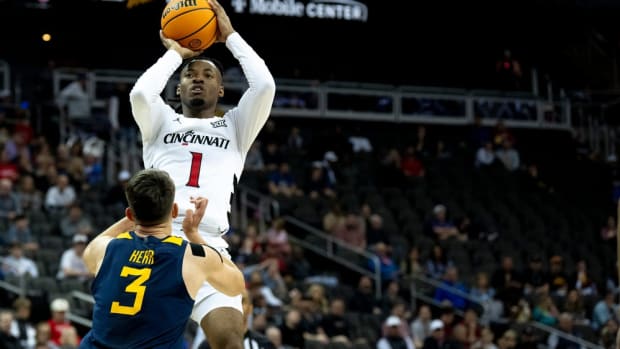 Cincinnati Bearcats guard Day Day Thomas (1) hits a jump shot as West Virginia Mountaineers guard Kerr Kriisa (3) defends in the first half of the Big 12 Conference tournament between Cincinnati Bearcats and West Virginia Mountaineers at T-Mobile Center in Kansas City, Mo., on Tuesday, March 12, 2024.  